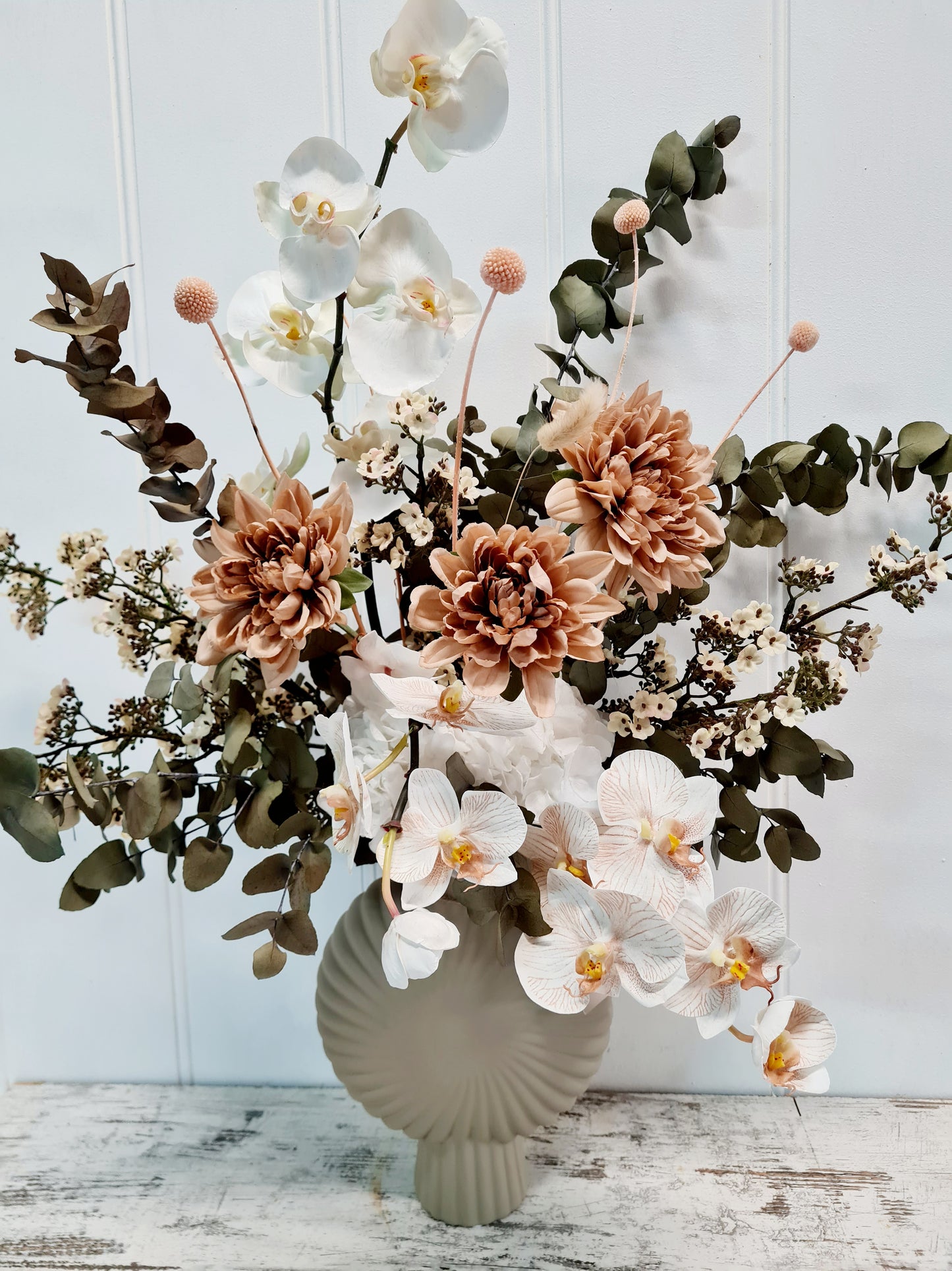 Featuring premium artificial Phalaenopsis orchids, blossoms, and dahlias, complemented by preserved eucalyptus gum foliage and hydrangeas.